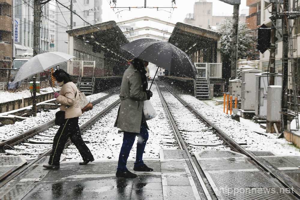People holding umbrellas walk on a snow-covered sidewalk in Tokyo on February 10, 2023, in Japan. The Meteorological Agency issued a heavy snow warning for central Tokyo. It may change to rain on Friday night and create hazardous road conditions on roads in the evening rush hour. (Photo by Rodrigo Reyes Marin/AFLO)