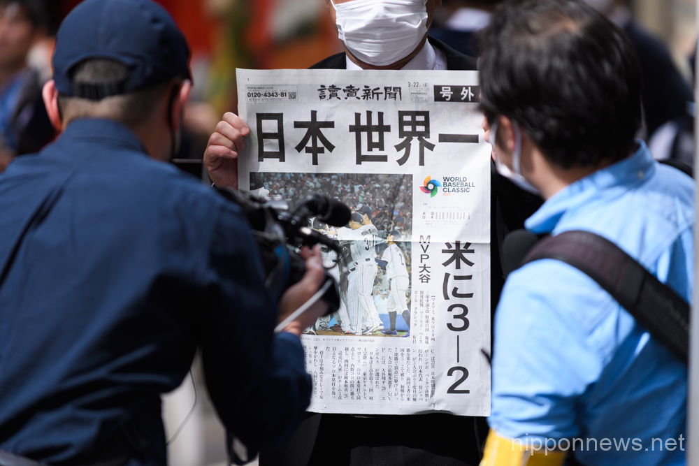 A baseball fan gets interviewed while holding a special edition version of the Yomiuri Newspaper celebrating Team Japan's victory in the 2023 World Baseball Classic final on March 22, 2023, in the Shibuya district of Tokyo, Japan. Japan defeated team USA 3-2 in the tournament final held in Miami to record their third championship title.(Photo by Keiichi Miyashita/AFLO)
